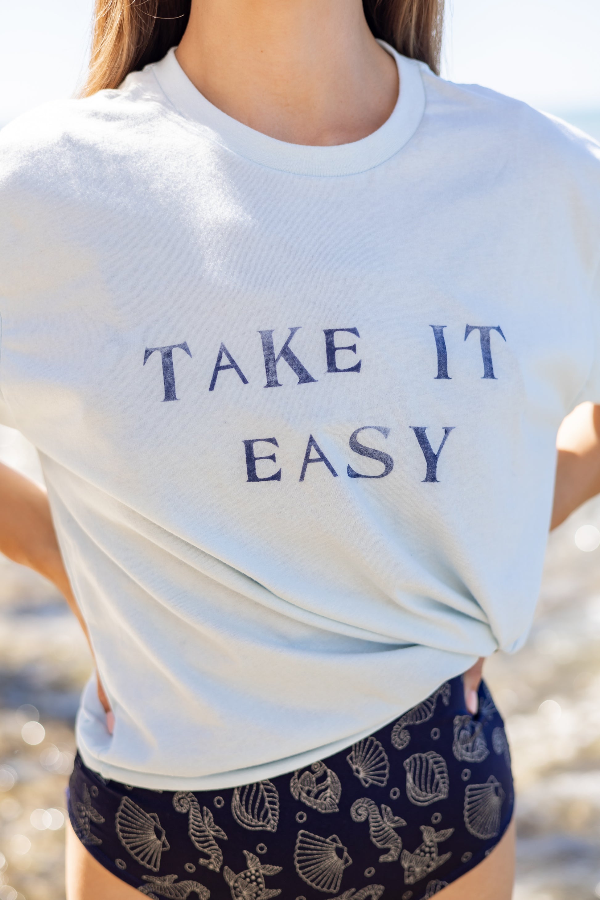 Can you really ever have enough comfy tees? We don't think so. Our white tees are made with organic cotton. Featuring a hand stamped lettering unique to each tee. This shirt is completely plant based and safe on your skin and our planet. This tee comes pre-cut at the hem for the perfect length, hitting right at your waistline. Pre-washed for ultimate comfort and added softness.  Hand Stamped  Perfect for high-waisted bottoms, can be tucked in  Raw Hemline, Relaxed Fit  Model is wearing size medium