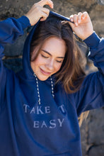 Just Take it Easy... Sometimes we all need a little reminder. Made from American grown cotton and recycled polyester this fleece is safe on your skin and our planet. This Unisex Hoodie features a hand stamped lettering unique to each item and custom drawcord made from surf leash string. Hand Stamped  Raw Hemline, Relaxed Fit  Model is wearing size medium